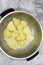 Part boiled potato in a metal colander strainer, ready to be roasted in oven.