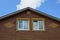 Part of a brown loft of bricks with windows on a sky background