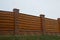 Part of a brown private fence in the grass outdoors against the sky