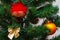 A part of christmas tree with red and orange balls, gold bow on faux Christmas tree. New years card, selective focus