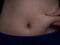 Part of female belly with excess fat close up. A starting to gain weight young caucasian woman squeezes fat on her waist with her