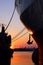 Part of forward and aft cargo ships with anchor and mooring rope that docked at port against sunset sky background in evening time