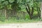 Part of a gray old wooden fence with broken boards in the green grass