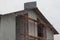 Part of a gray unfinished house with an empty window in the attic