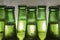 Part of green beer bottles in drops of condensation on a light background.