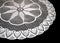 A part of isolated crocheted white doily with pattern with cones and arches a black background. Round decorative cotton doily