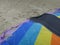Part of a kite in rainbowcolors with black threads laying on the beach of Velsen Netherlands