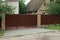 Part of a long metallic brown fence and a large gate outside in the grass