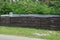 Part of a long rural fence of brown wooden planks outdoors