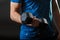 A part of man`s torso, wear blue t-shirt with gymnastic dumbbell in right hand