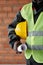 Part of modern foreman in reflective jacket holding hardhat and blueprint