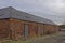 Part of an old Agricultural Farm Store Complex with metal shutter doors built into the red Stone Building.