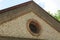 Part of an old brown brick attic with a small round  window