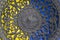Part of openwork cast-iron plate on yellow and blue backgrounds