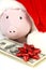 Part of piggy bank with Santa Claus hat and stack of money american hundred dollar bills with red bow