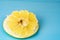 Part of the pomelo peeled from the fruit on a blue background