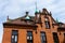 Part of the red brick wall, windows and a fragment of the roof of an old residential building against the sky.