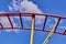 Part of a roller coaster. Background of blue sky and white clouds.