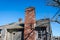 Part of tiled roof with brick chimney against clouds