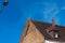 Part of a tiled roof with a dormer window and chimney.