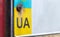 Part of the Ukrainian license plate on the bumper close-up. The symbol of nationality on the background of the colors of the flag