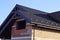 Part of an unfinished house with a brown brick attic and an empty window under a tiled roof