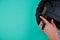 Part of an upside-down robot vacuum cleaner with an edge on a blank blue background. A woman\'s hand turns on a round vacuum