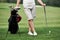 Part view of man standing on the green grass with golf equipment