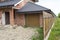 Part view of modern two-storied not finished new brick family cottage house with steep brown shingled roof, attached garage, tempo