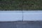 Part of a white concrete curb on a gray asphalt