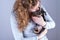 Part of a woman with brown curls, she lovingly kisses a tiny Jack Russel Terrier puppy in her arms