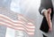 Part of a woman offering her hand against fluttering american flag and buildings