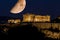 Parthenon of Athens under a huge magnificent moon, at dusk time