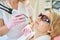 Partial female cosmetologist doing laser epilation of face of adult woman