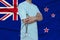 Partial photograph of a doctor in uniform against the backdrop of the New Zealand national flag on delicate shiny silk, the