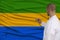 Partial photograph of the doctor in uniform against the background of the national flag of Gabon on delicate shiny silk, the