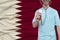 Partial photograph of a doctor in uniform against the background of the national flag of Qatar on delicate shiny silk with soft