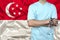 Partial photograph of a doctor in uniform against the background of the national flag of Singapore on delicate shiny silk, the