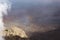 A partial rainbow reflecting of hazy clouds over a red, barren landscape at the Leleiwi Overlook in Haleakala National Park