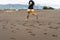 Partial rear view of a barefoot man running on the beach