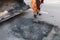 Partial repair of the asphalt road. The worker cleans a bad part of the road