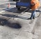 Partial repair of the asphalt road. The worker sprays bitumen on the asphalt surface