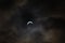 Partial solar eclipse - moon covers sun, dark clouds, celestial drama - crescent sun - atmospheric mood