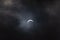 Partial solar eclipse - moon covers sun, dark clouds, celestial drama - crescent sun - atmospheric mood