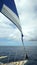 Partial view bow of sailboat on the Pacific Ocean and sail against ocean and blue overcast sky to horizon