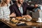 Partial view of couple sitting at table while man paying for dinner