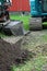 Partial view of excavator, shovel and a pile of soil in yard