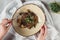 partial view of female hands and soba with tofu and vegetables decorated with germinated seeds of sunflower