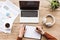 partial view of man making notes at workplace with cup of coffee, papers, headphones and laptop