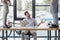 partial view of men kicking soccer ball on table while irritated colleague using laptop in office